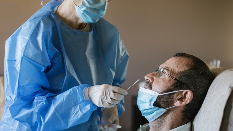 Doctor doing a nasal PCR test on a patient at nursing home