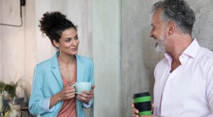 Man and woman with coffee cups conversing at the office
