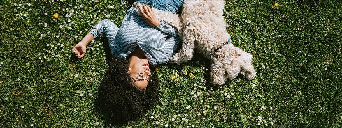 A Young Woman Rests in the Grass With Pet Poodle Dog