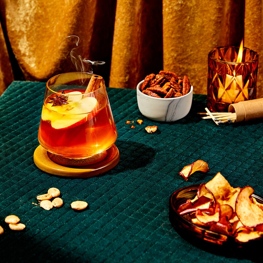 Christmas rum sour punch cocktail on tabletop with candles and snacks