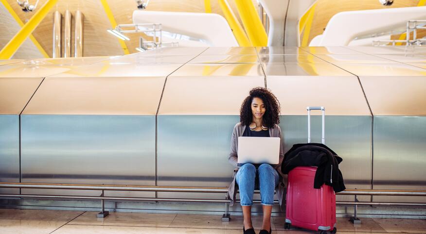 attractive black Woman at the airport sitting and working with laptop