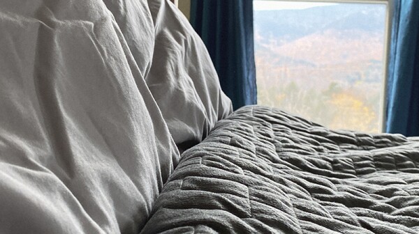 A weighted blanket on a bed with a window in the background