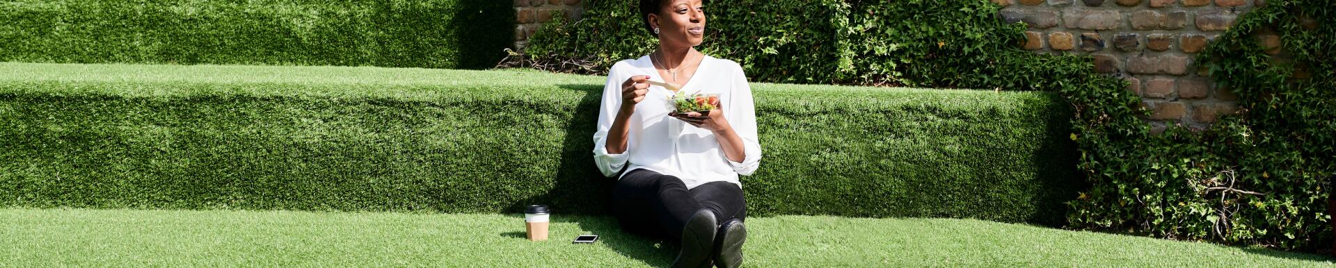 A woman practicing mindful eating sitting in the grass