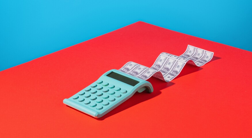 Calculator printing dollar bills on bright background