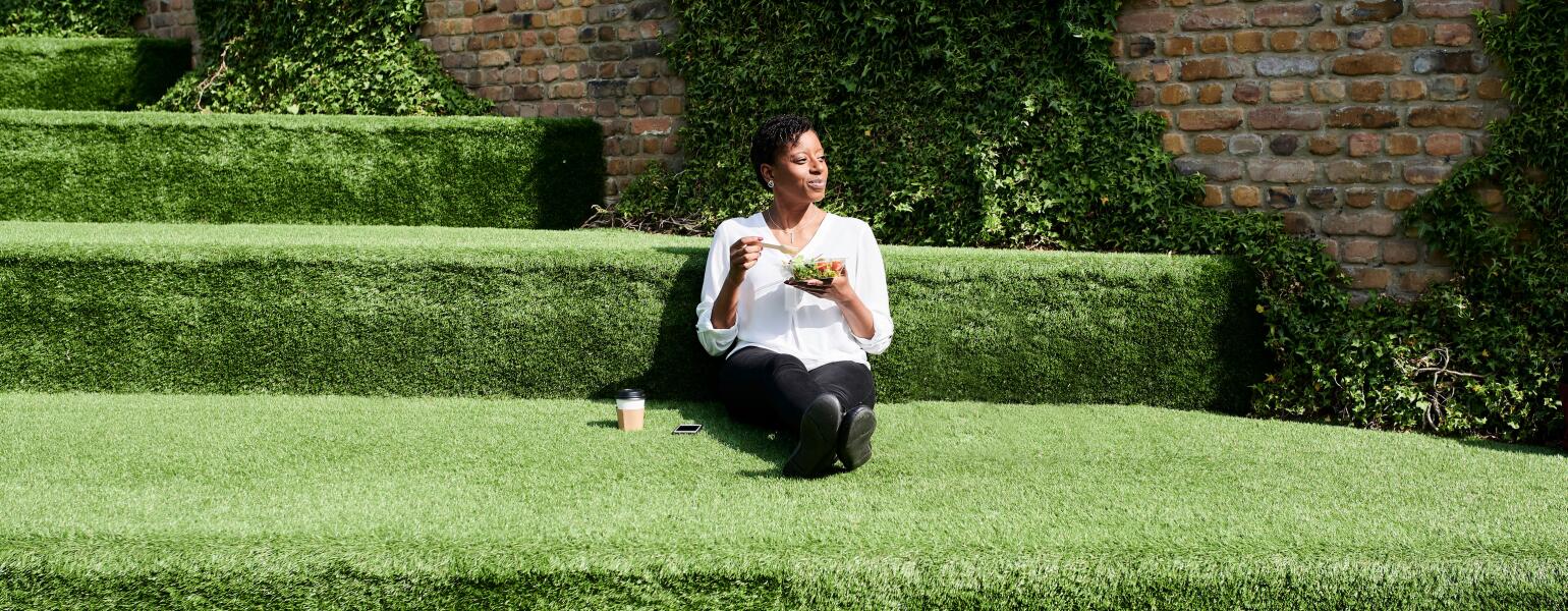 A woman practicing mindful eating sitting in the grass