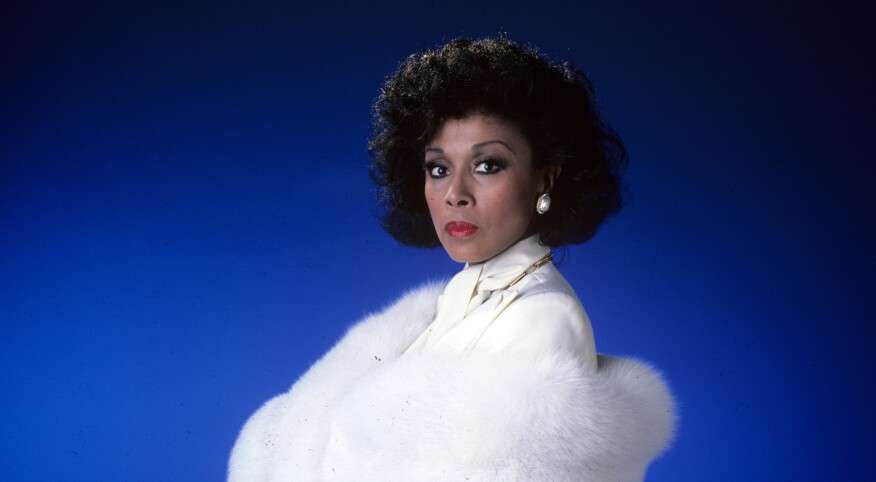 Diahann Carroll on blue background in white suit from TV show Dynasty