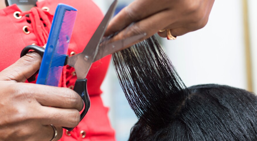 The hairdresser arranges the hair of her client by cutting them with scissors.