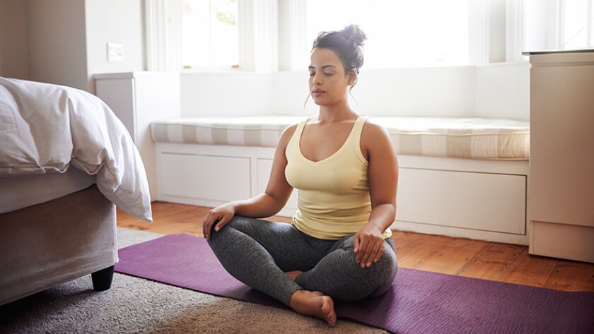 woman beginning her day by meditating in her bedroom