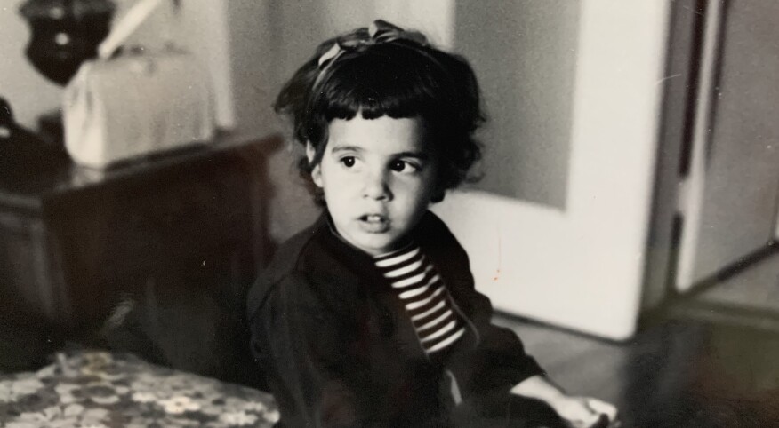 a young child looks off to the left dressed in a black and white striped shirt