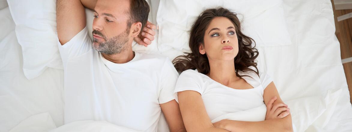 Couple in bed looking irritated