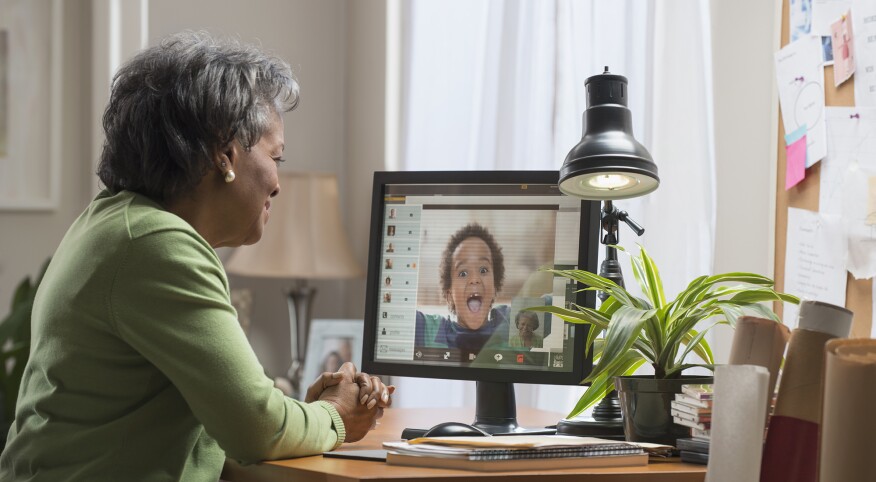 Black woman video conferencing with grandson on computer
