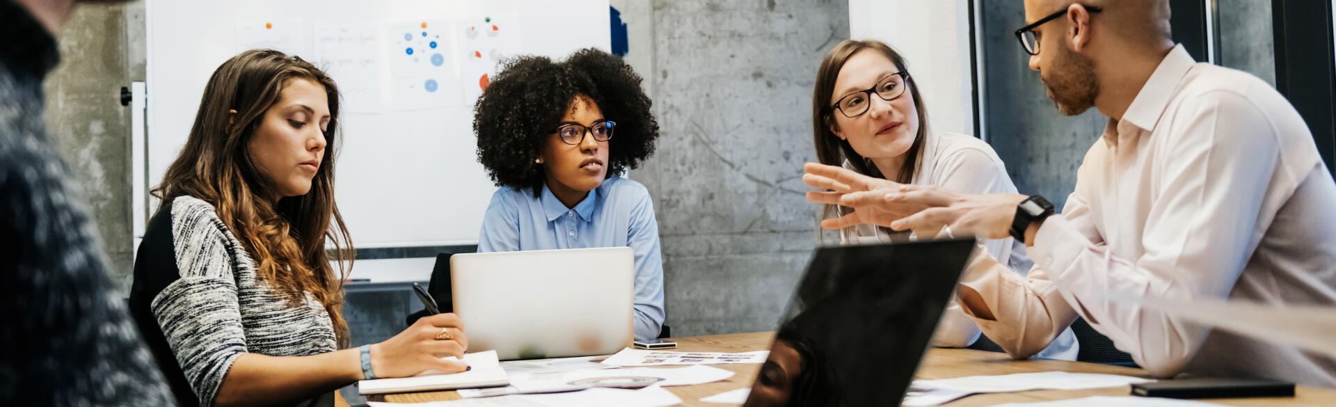 Women in meeting being talked over by a man using hand gestures