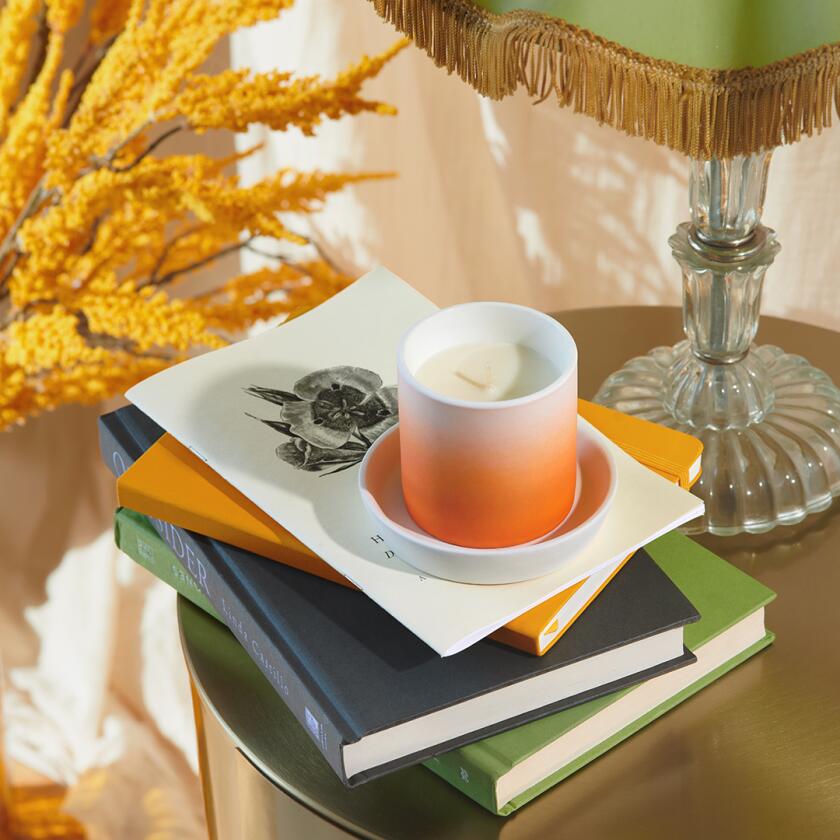 Ombre white and orange candle on books on a small table