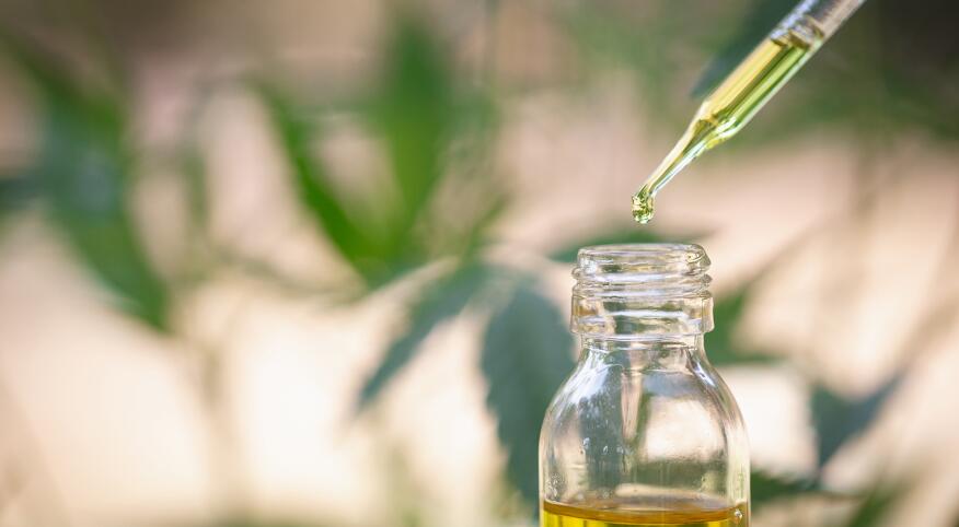 Jar with CBD oil being taken out by a dropper.