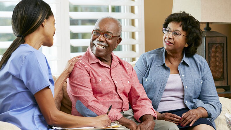 older couple talk to a nurse in their home