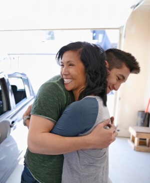 A middle aged mom hugs her son in the garage