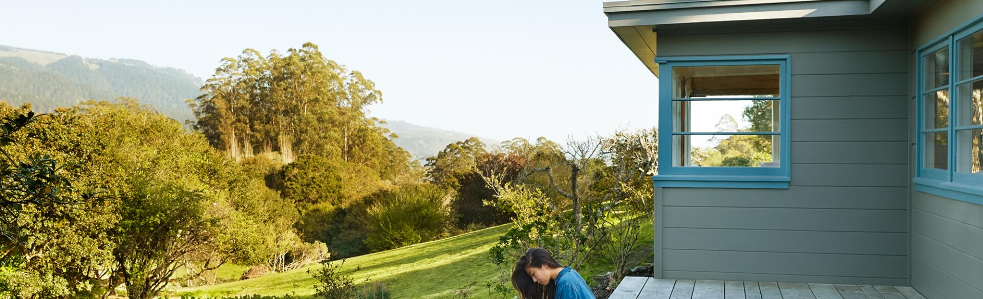 Woman sitting alone on her back porch surrounded by nature