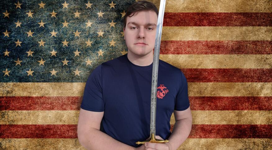 The authors son holding a marine sword standing in front of american flag