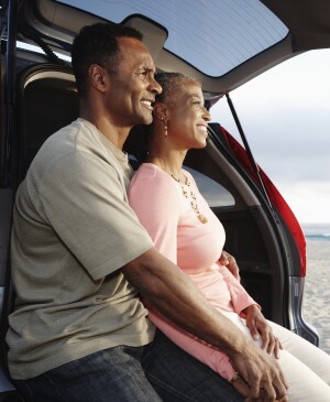 Black couple sitting on hatchback enjoying the beach