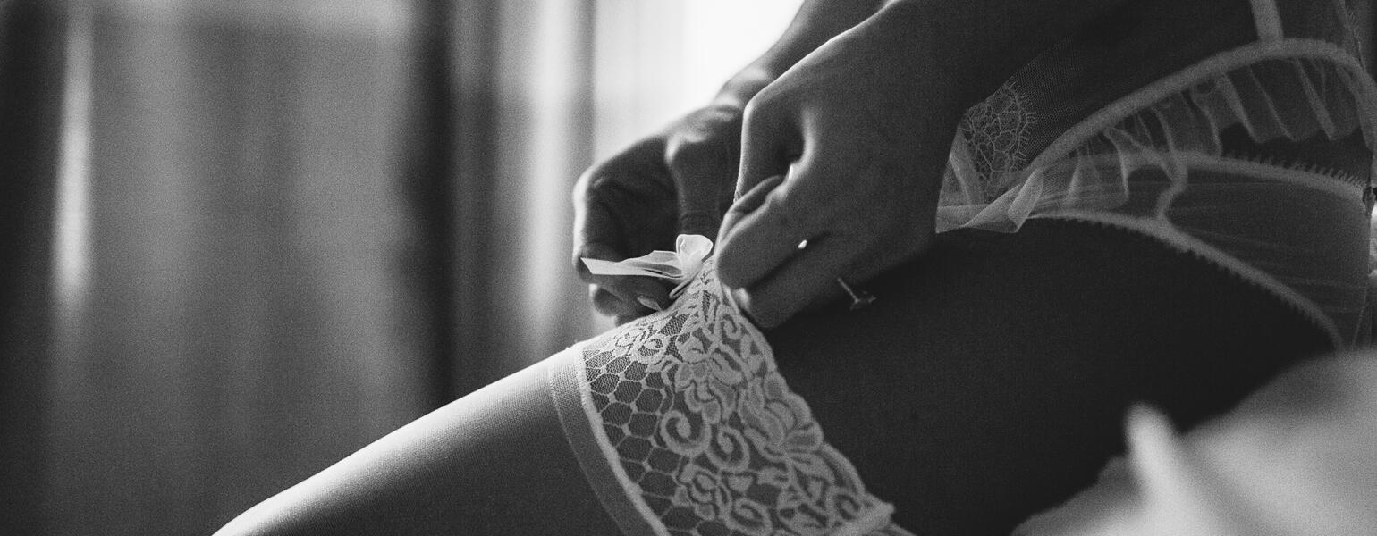 Boudoir photo shoot with woman in lingerie and showing garter on her thigh