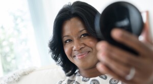 Black woman admiring her hair in a compact mirror