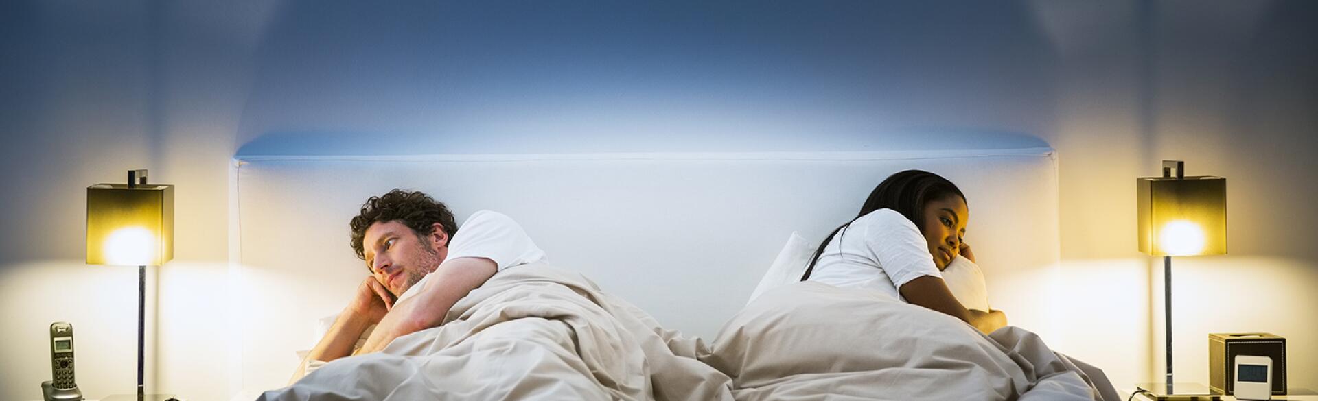 couple lying in bed facing opposite directions