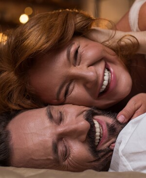 Man and woman cuddling and smiling in bedroom