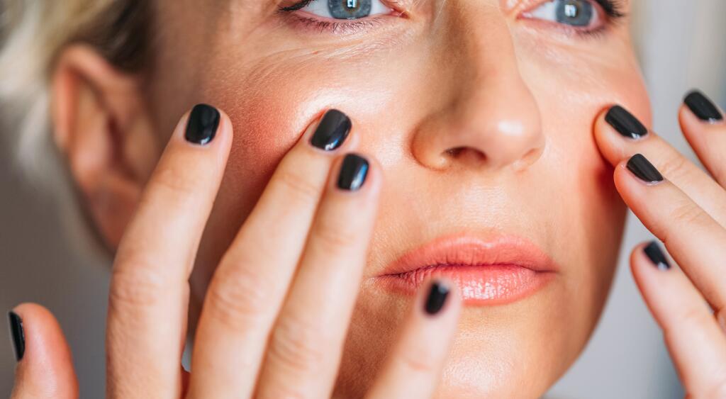 Woman In Her 40s touching her face gently
