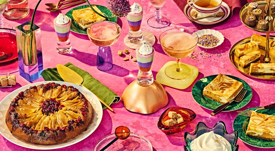 Table of beautiful desserts including cake, bars and pudding on bright pink background