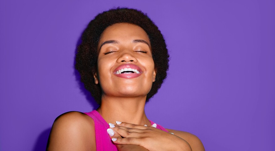 Woman looking joyful with her eyes closed on a purple background 