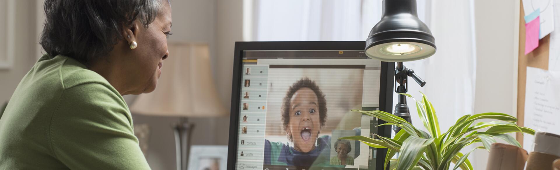 Black woman video conferencing with grandson on computer