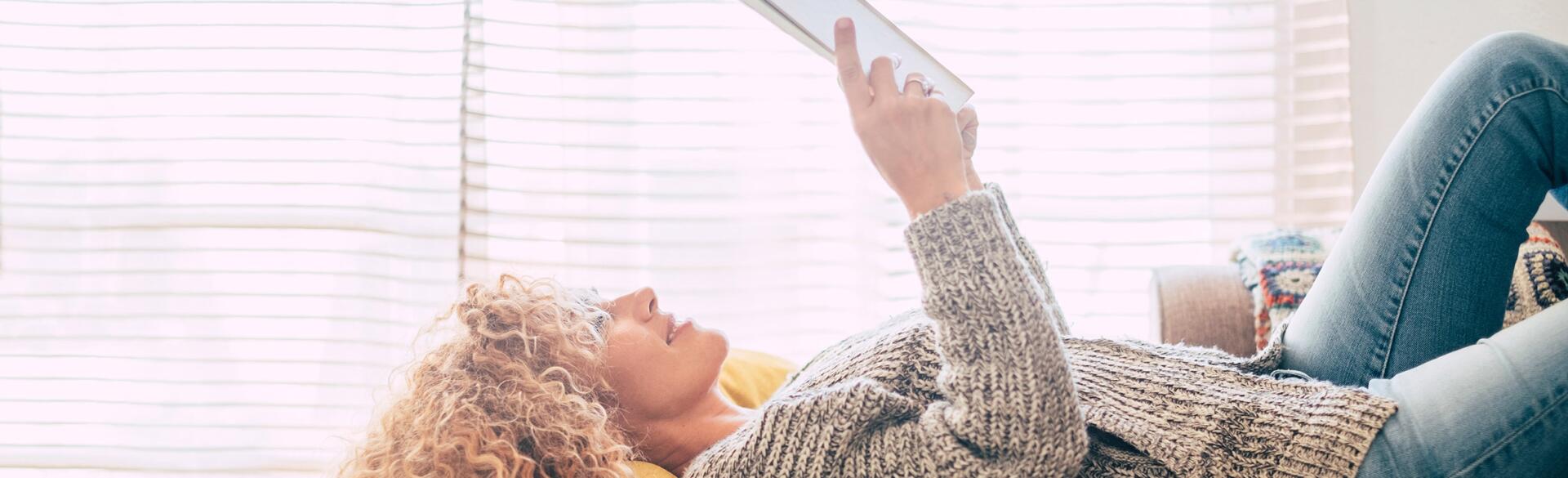 woman reading a book while lying down on a couch