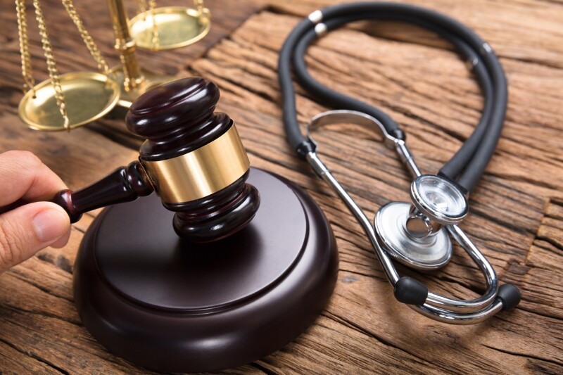 Judge's Hand Hitting Mallet By Stethoscope And Justice Scale