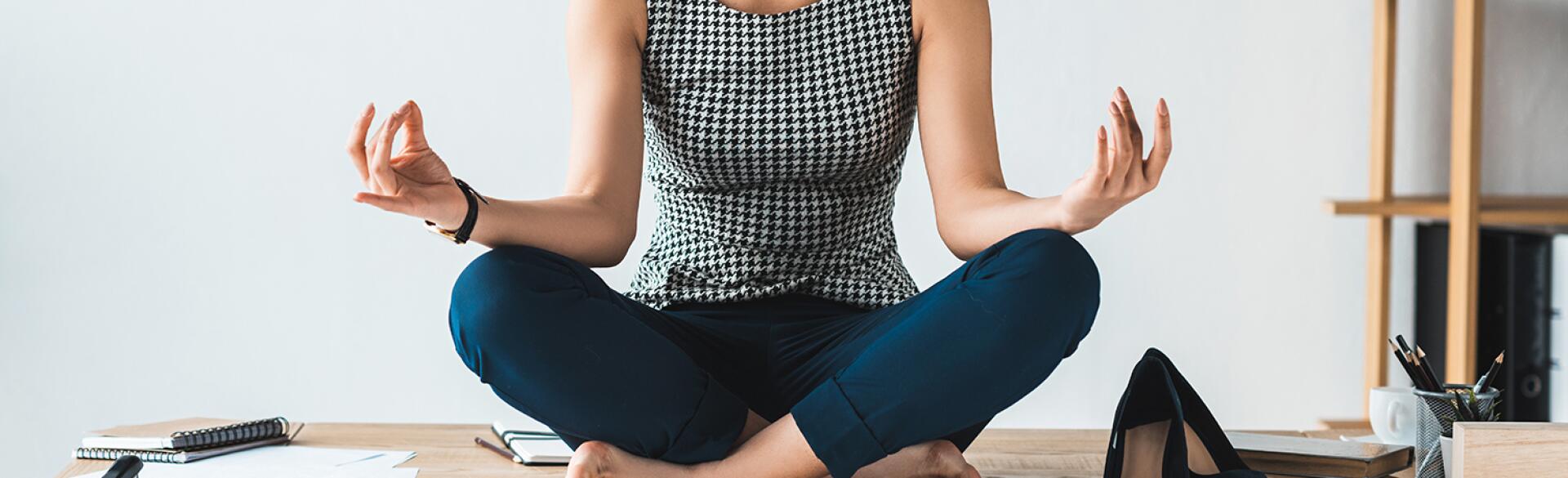 imge_of_black_woman_sitting_cross_legged_on_office_desk_GettyImages-949851136_crop_1540