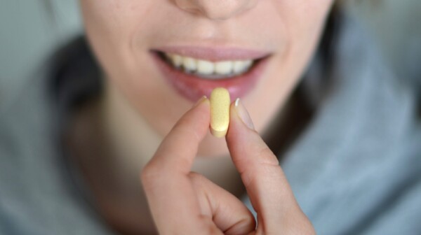 Woman about to swallow capsule