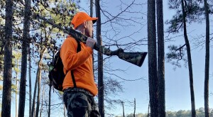 Man in orange hunting and holding a rifle
