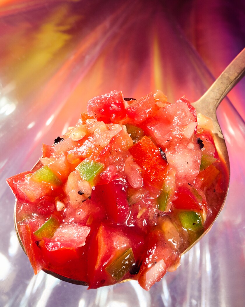 Closeup of chunky tomato salsa on spoon with colorful background
