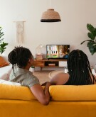 two Black women watch television in the living room