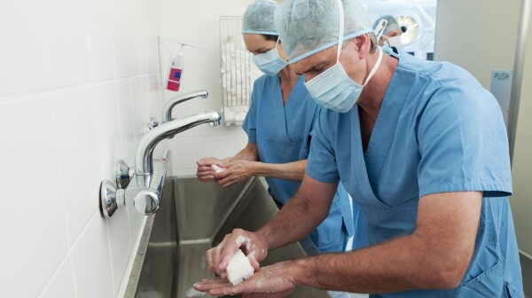 Surgeons in scrubs washing hands at sink
