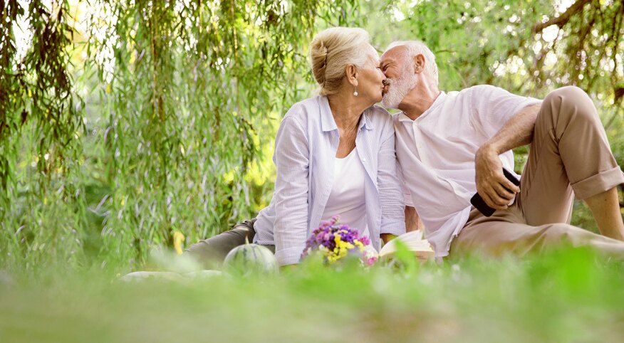 Older couple kissing outside on a blanket