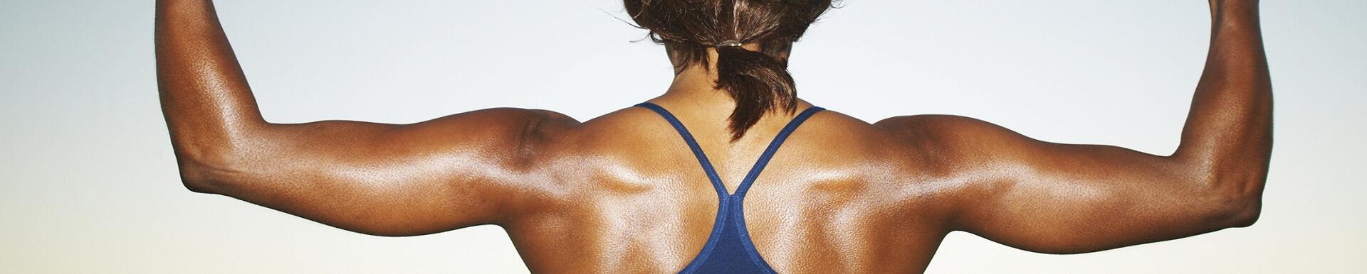 Woman bodybuilder flexing arms, top section, rear view