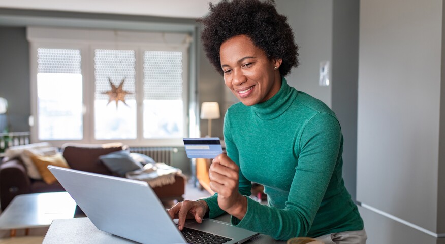 Woman with credit card at home doing online shopping