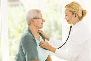 Female doctor listening to senior patient's heart.