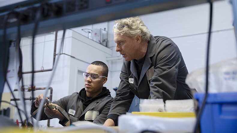 Male machinists examining equipment in factory