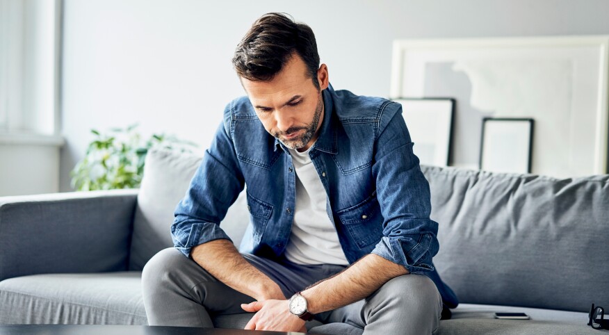 Depressed man sitting at home on the couch