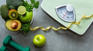 green vegetables and fruit, dumbbells, measuring tape, and body scale