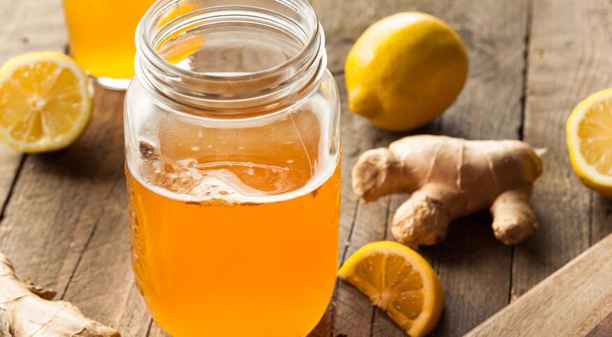 Kombucha in a mason jar surrounded by ginger lemon and oranges