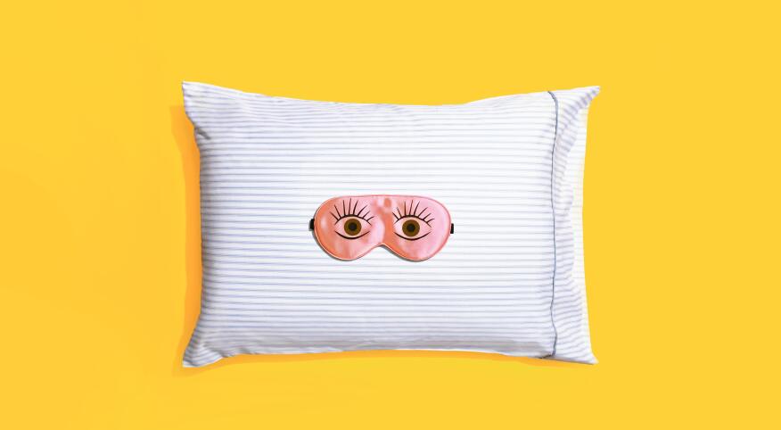 Sleeping mask on a striped pillow and yellow background