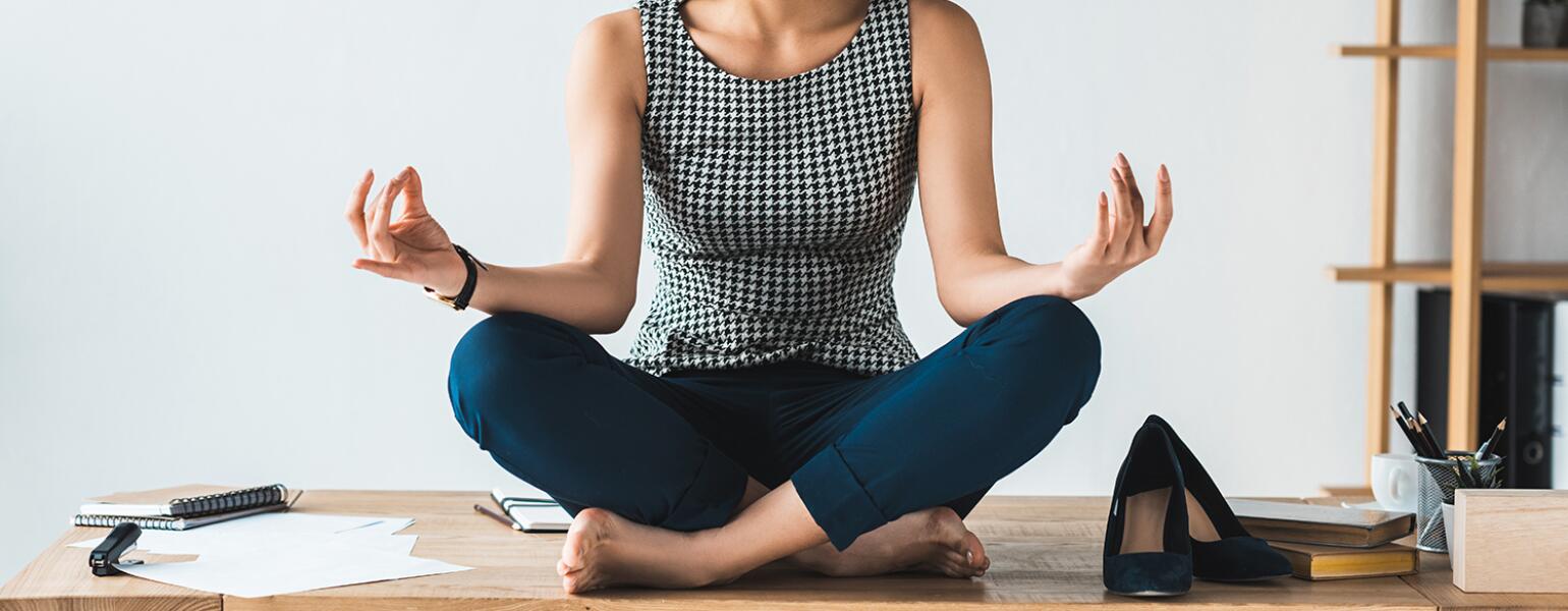 imge_of_black_woman_sitting_cross_legged_on_office_desk_GettyImages-949851136_crop_1540