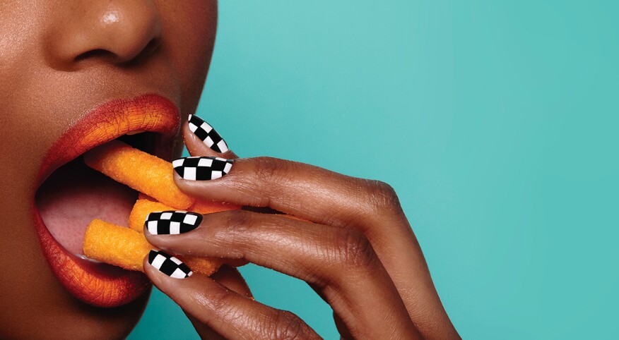 Woman eating junk food on bright studio background